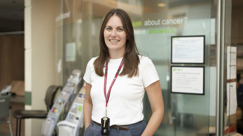 Anna Van Osch standing outside her office wearing a white tee shirt